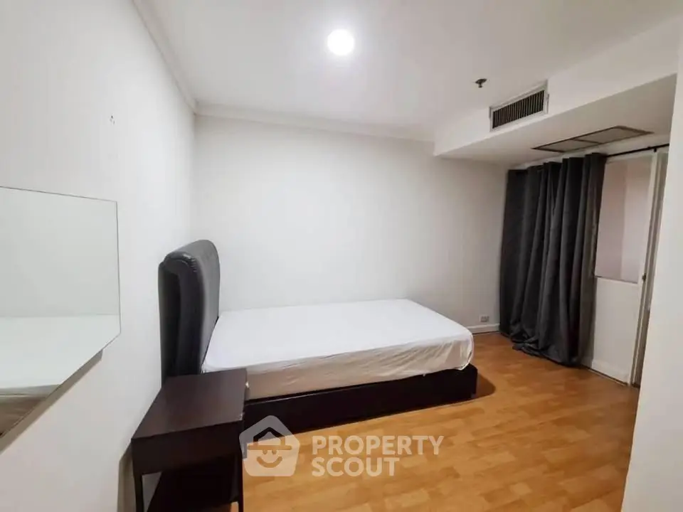 Spacious bedroom with modern design and wooden flooring in a cozy apartment.