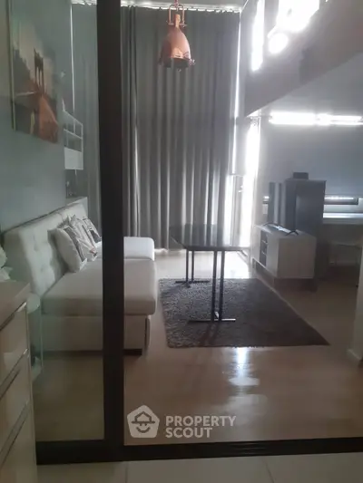 Modern living room with stylish decor and natural light, featuring a cozy sofa and sleek furniture.