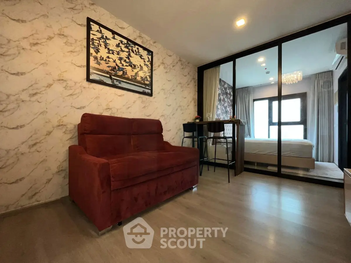 Modern apartment interior with stylish living room and cozy bedroom separated by glass doors.