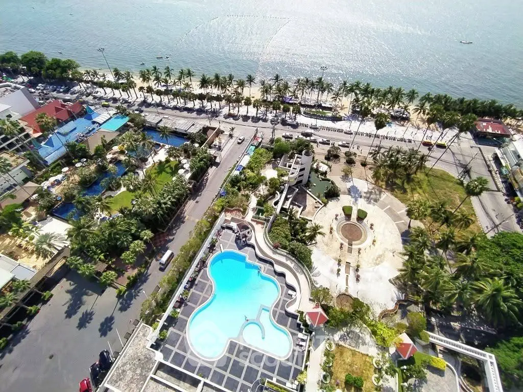 Stunning aerial view of beachfront property with pool and lush gardens