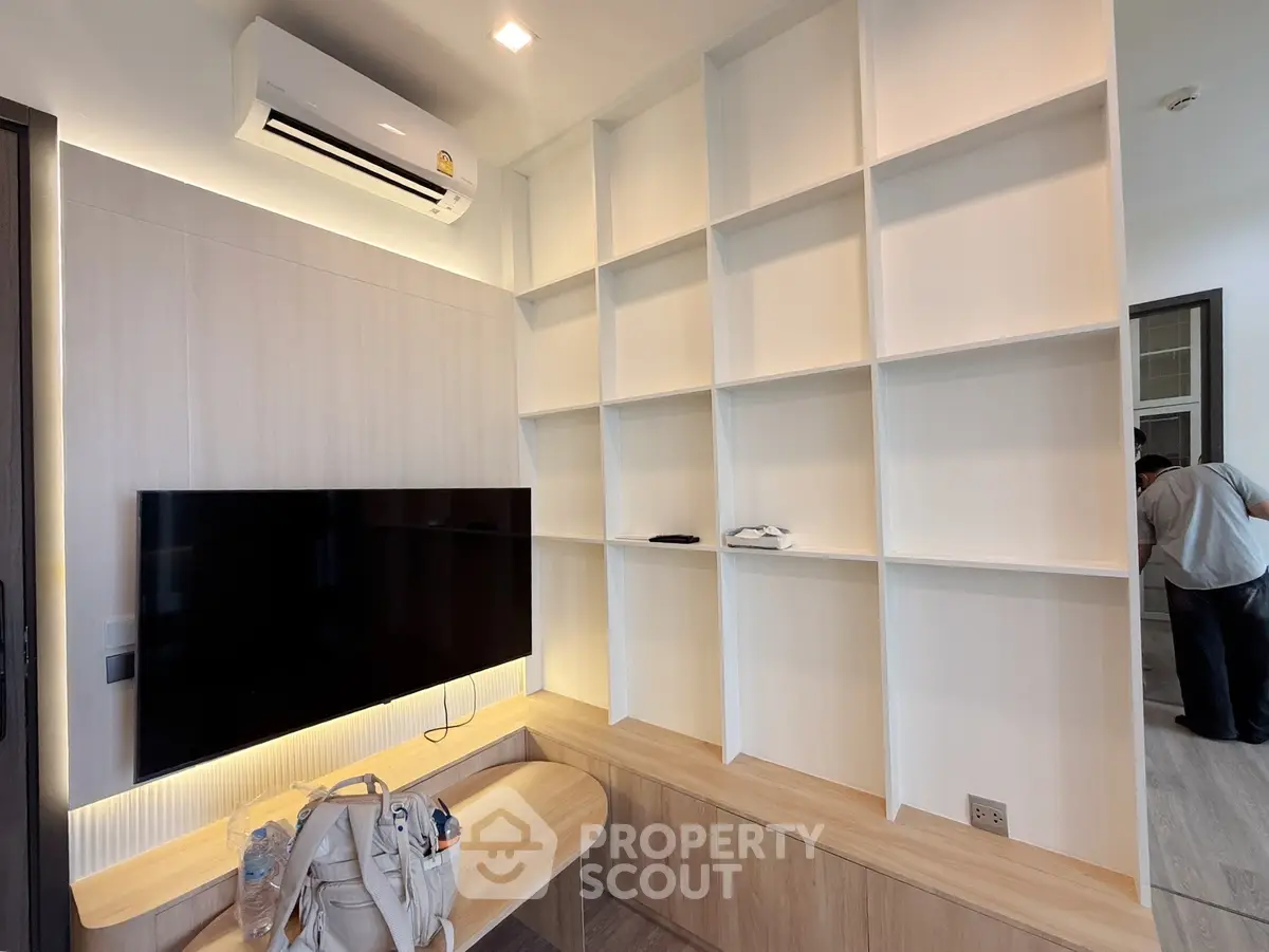 Modern living room with built-in shelves and wall-mounted TV, featuring sleek design and ample storage space.
