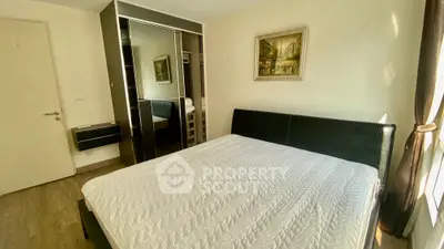 Modern bedroom with sleek black bed and mirrored wardrobe in bright apartment