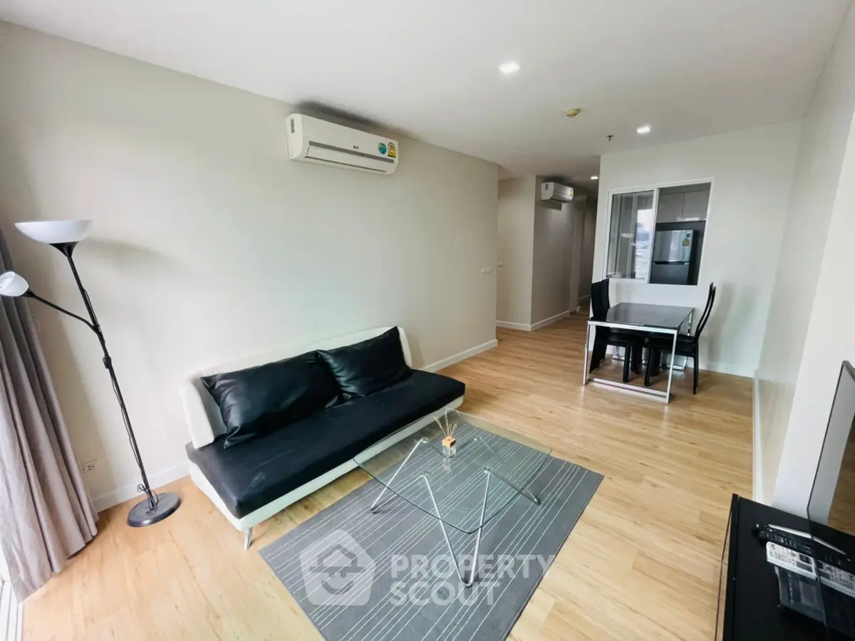 Modern living room with sleek furniture and dining area in open layout apartment.