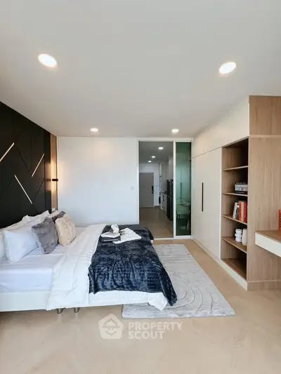 Modern bedroom with stylish decor and built-in shelving, featuring cozy bedding and elegant lighting.