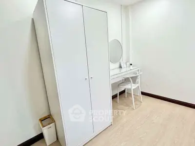 Minimalist bedroom with white wardrobe and vanity desk, perfect for modern living.