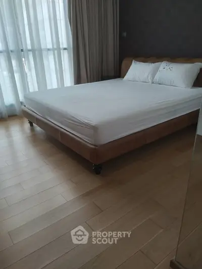 Spacious bedroom with large windows and wooden flooring