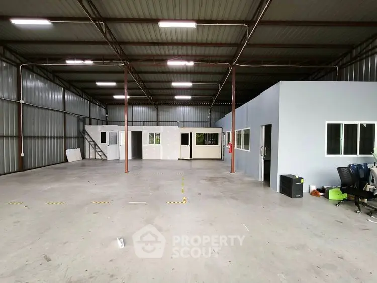 Spacious industrial warehouse interior with office space and high ceilings.