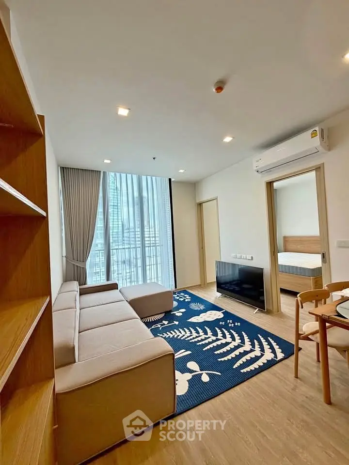 Modern living room with large windows and stylish decor in a high-rise apartment.
