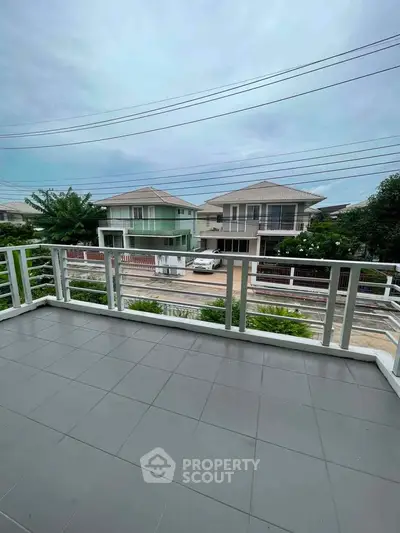 Spacious balcony with a view of suburban houses and clear skies, perfect for relaxation.