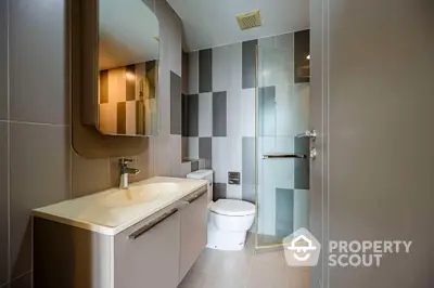 Modern bathroom with sleek design, featuring a large mirror, stylish sink, and glass shower enclosure.