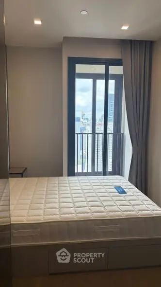 Modern bedroom with large window and city view, featuring a comfortable bed and sleek design.