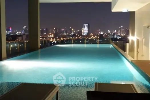 Luxurious rooftop infinity pool with stunning city skyline view at night.