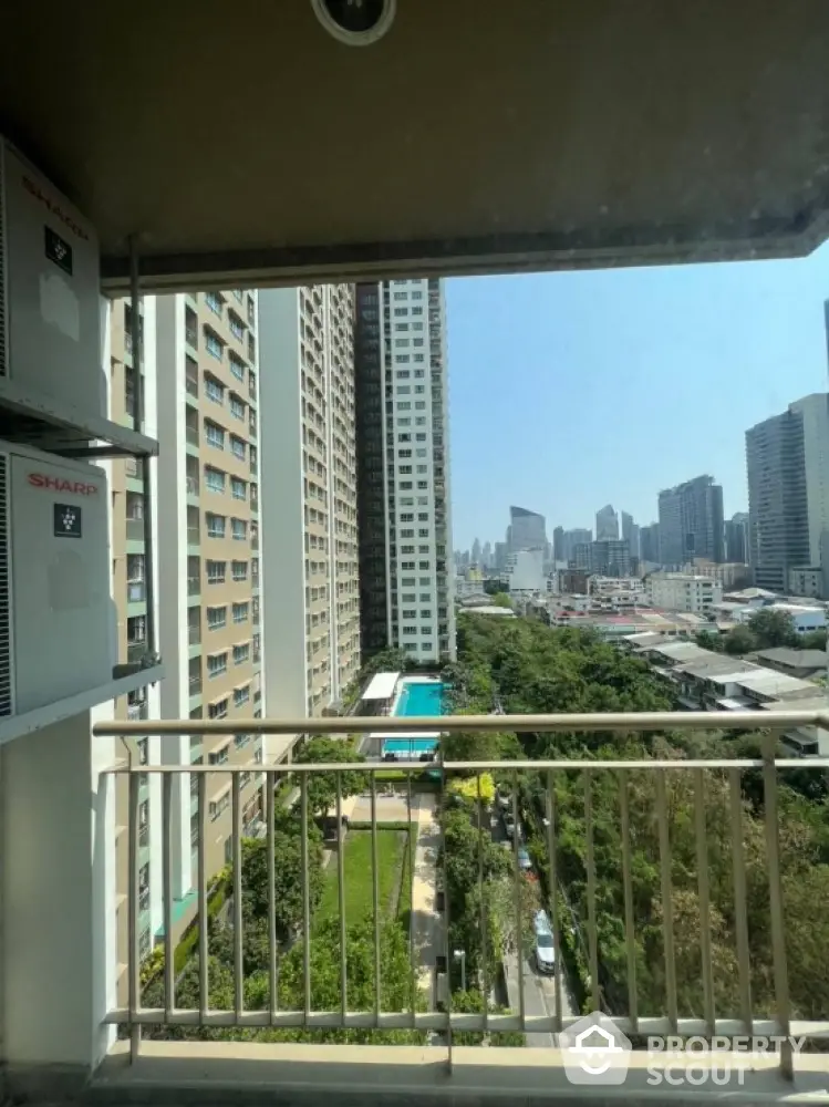 Stunning city view from high-rise balcony overlooking pool and greenery