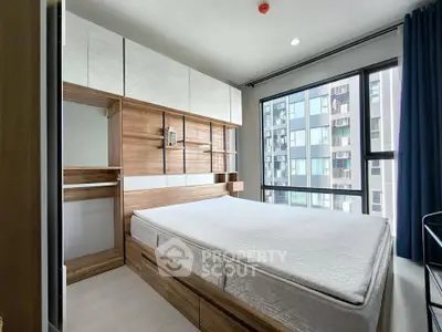 Modern bedroom with large window and built-in wooden storage in urban apartment