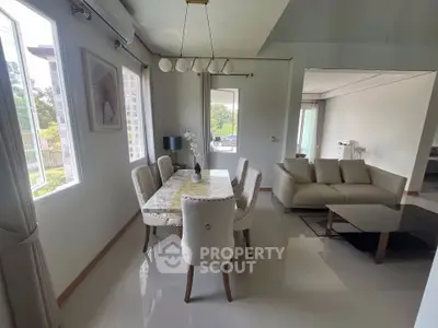 Elegant living and dining area with modern furniture and large windows offering natural light.