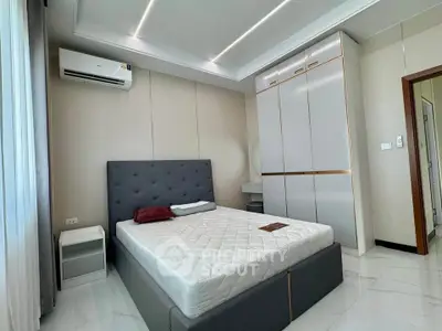 Modern bedroom with sleek design, featuring a stylish bed, built-in wardrobe, and air conditioning.