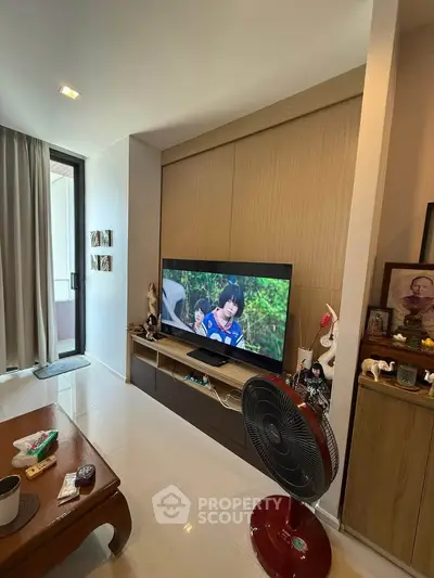 Modern living room with TV, fan, and balcony access in stylish apartment.