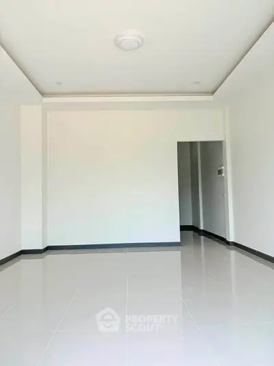 Spacious empty room with glossy white tiles and modern ceiling light, perfect for customization.