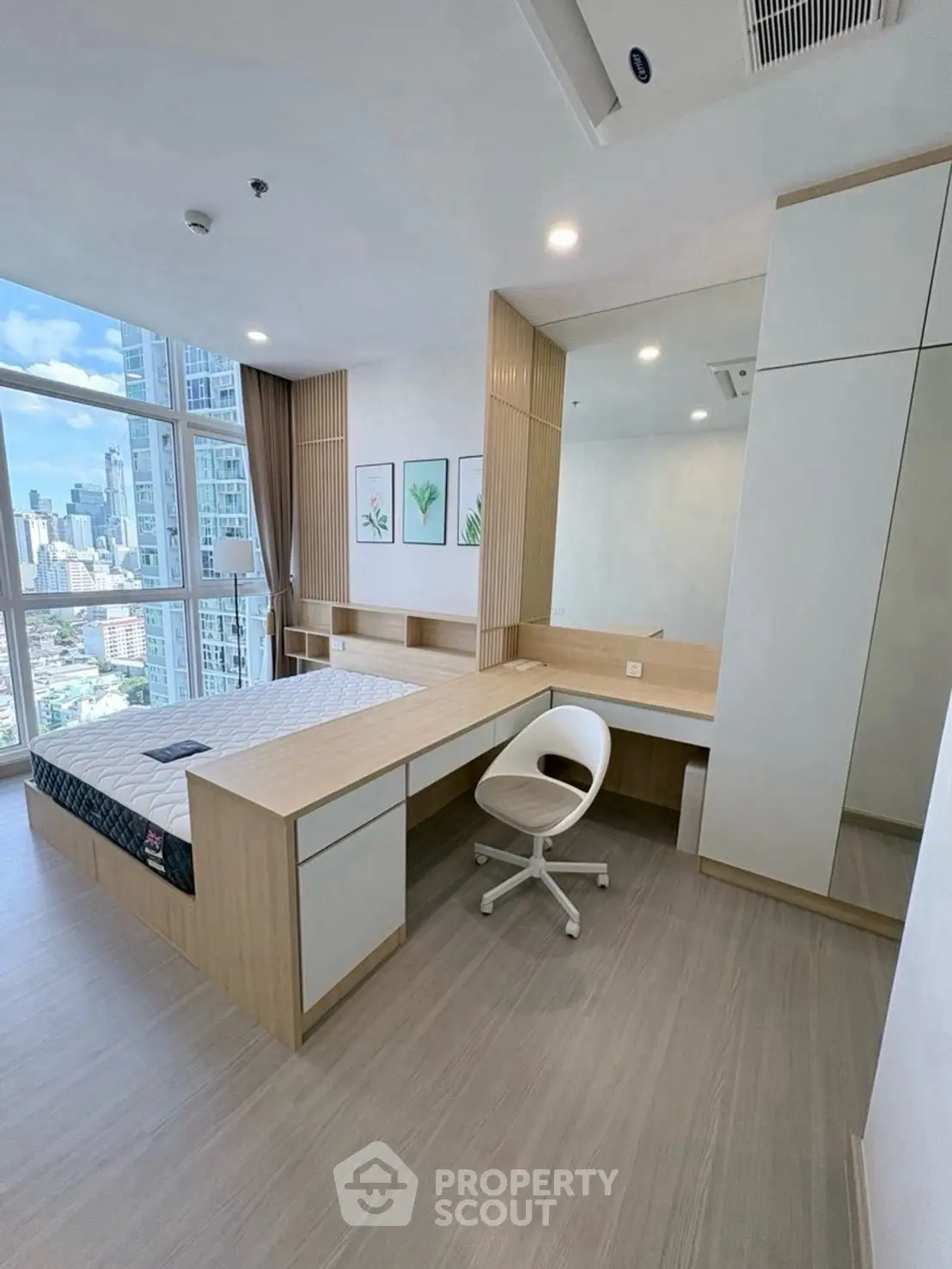 Modern bedroom with city view, featuring built-in desk and stylish decor.