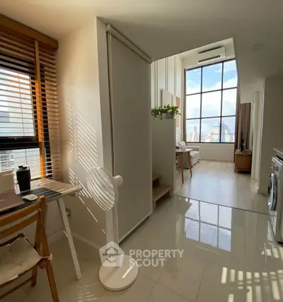 Modern apartment with large windows and natural light, featuring a cozy living area and stylish decor.