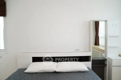 Modern minimalist bedroom with sleek white furniture and cozy bedding.