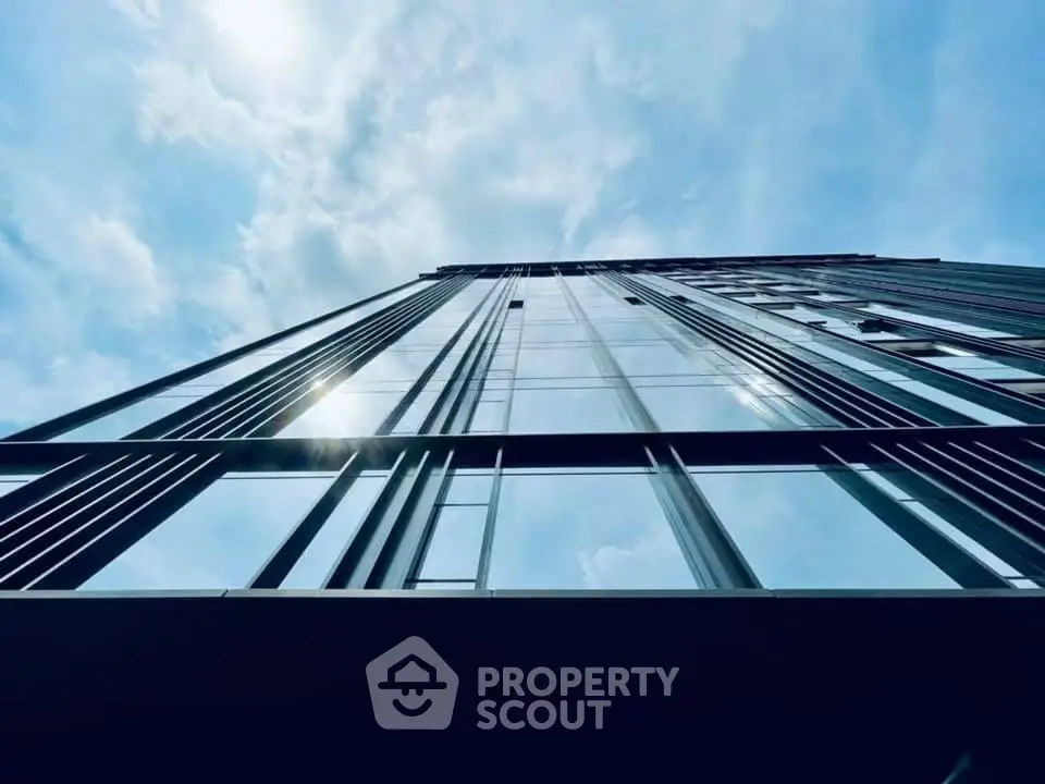 Stunning modern skyscraper with reflective glass facade against a bright blue sky.