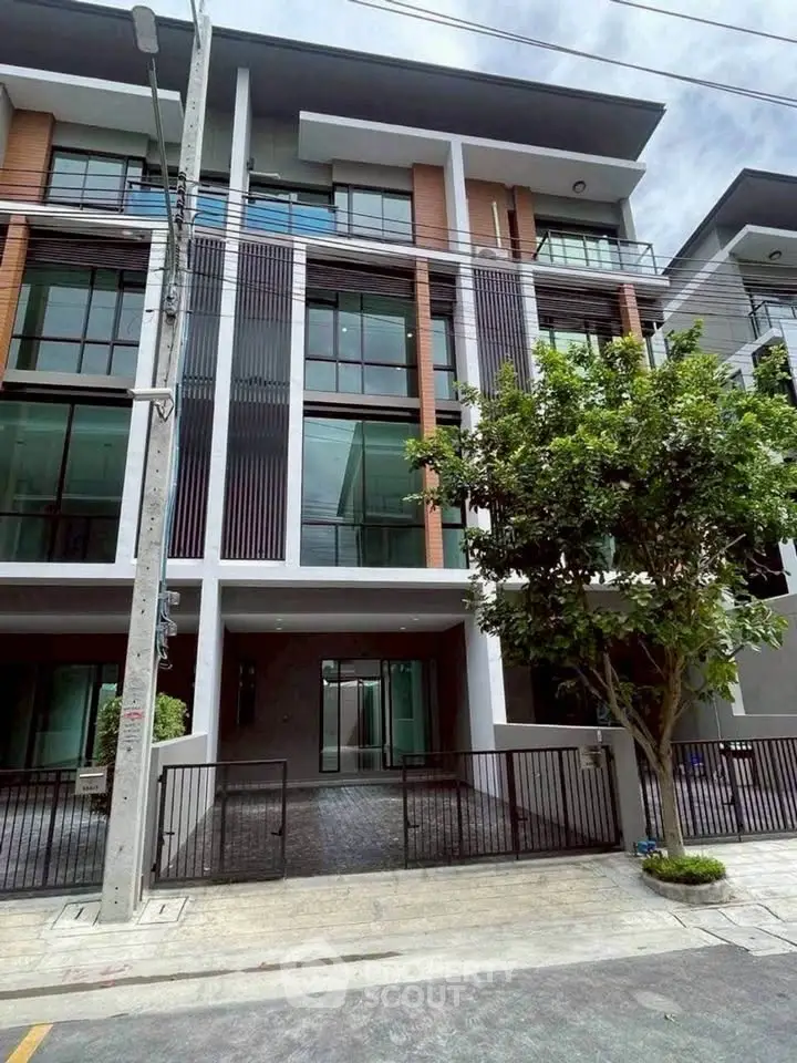 Modern multi-story residential building with sleek facade and gated entrance.