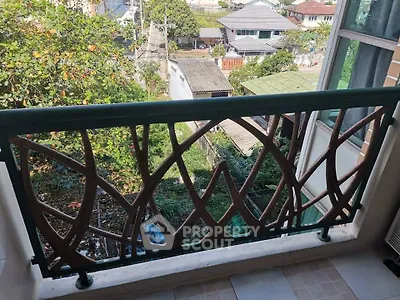 Charming balcony with artistic railing offering a lush green view in a serene neighborhood.