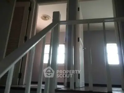 Interior view of a staircase leading to a hallway with doors and windows.