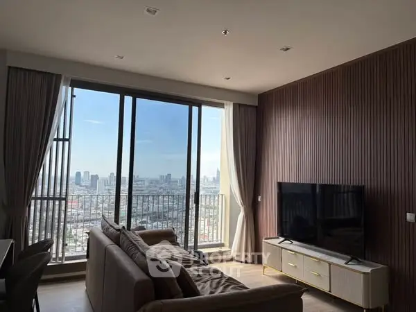 Modern living room with city view and large windows in high-rise apartment.