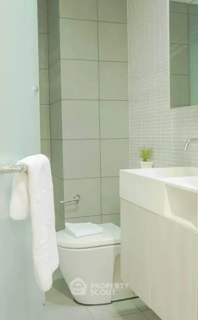 Modern bathroom with sleek design, featuring a white sink, toilet, and stylish tiles.