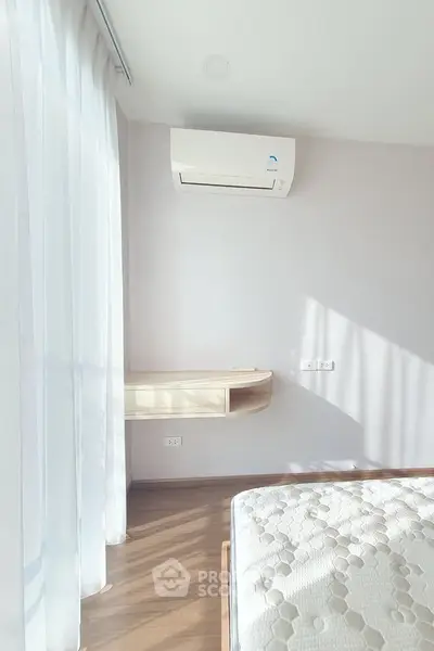 Bright bedroom with air conditioning and natural light, featuring a cozy mattress and elegant curtains.