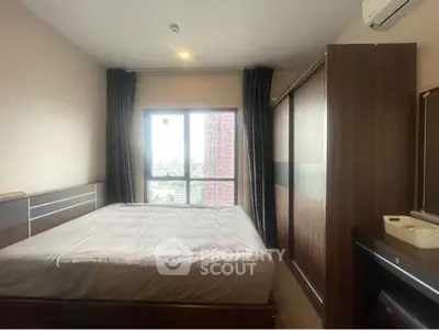 Cozy bedroom with large window offering city view, featuring modern furniture and ample storage space.