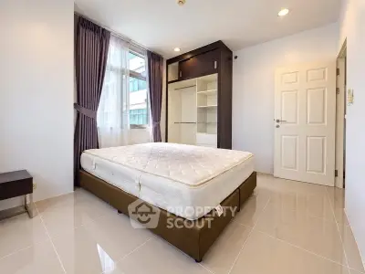Spacious bedroom with large window and built-in wardrobe in modern apartment.
