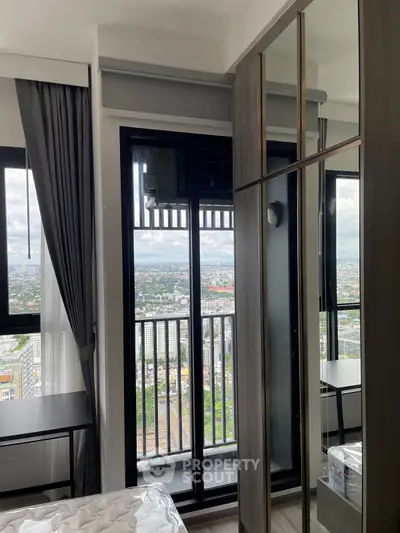 Modern bedroom with city view and balcony access in high-rise apartment