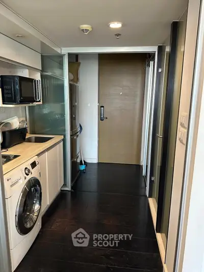 Modern compact kitchen with washing machine and sleek appliances in a stylish apartment.