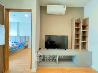 Modern living room with TV and air conditioning, adjacent to a stylish bedroom.