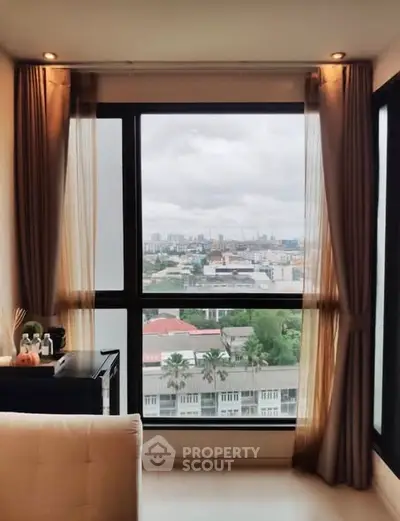 Cozy living room with city view through large window and elegant curtains.
