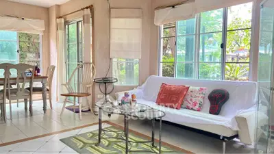 Charming living room with large windows and cozy seating area, perfect for relaxation.