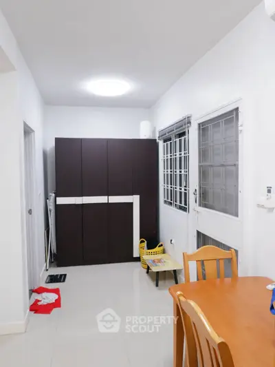 Modern dining area with wooden table and chairs, sleek storage cabinet, and bright lighting.
