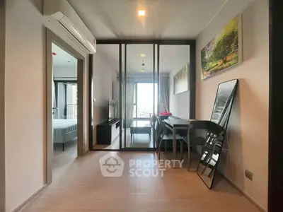 Modern apartment interior with open layout, featuring a dining area and a view into the bedroom.