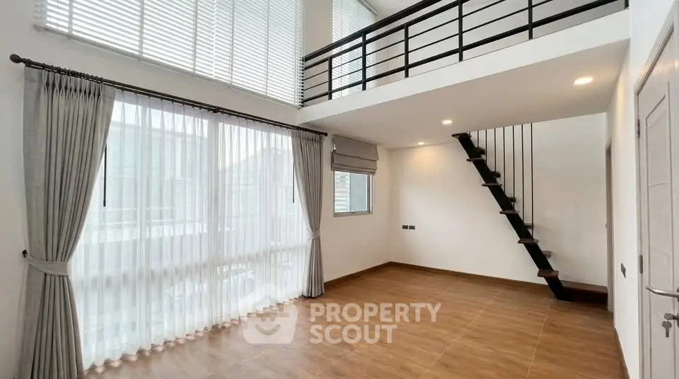 Spacious modern living room with high ceilings and mezzanine in a bright, airy home.