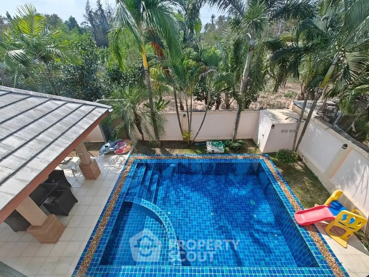 Stunning tropical pool with lush greenery and slide, perfect for family relaxation and entertainment.