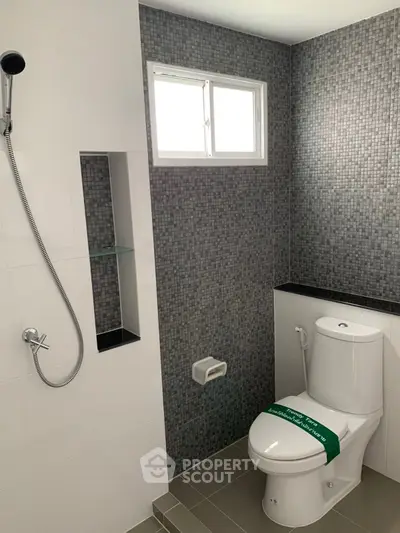 Modern bathroom with sleek design and tiled walls, featuring a shower and toilet.