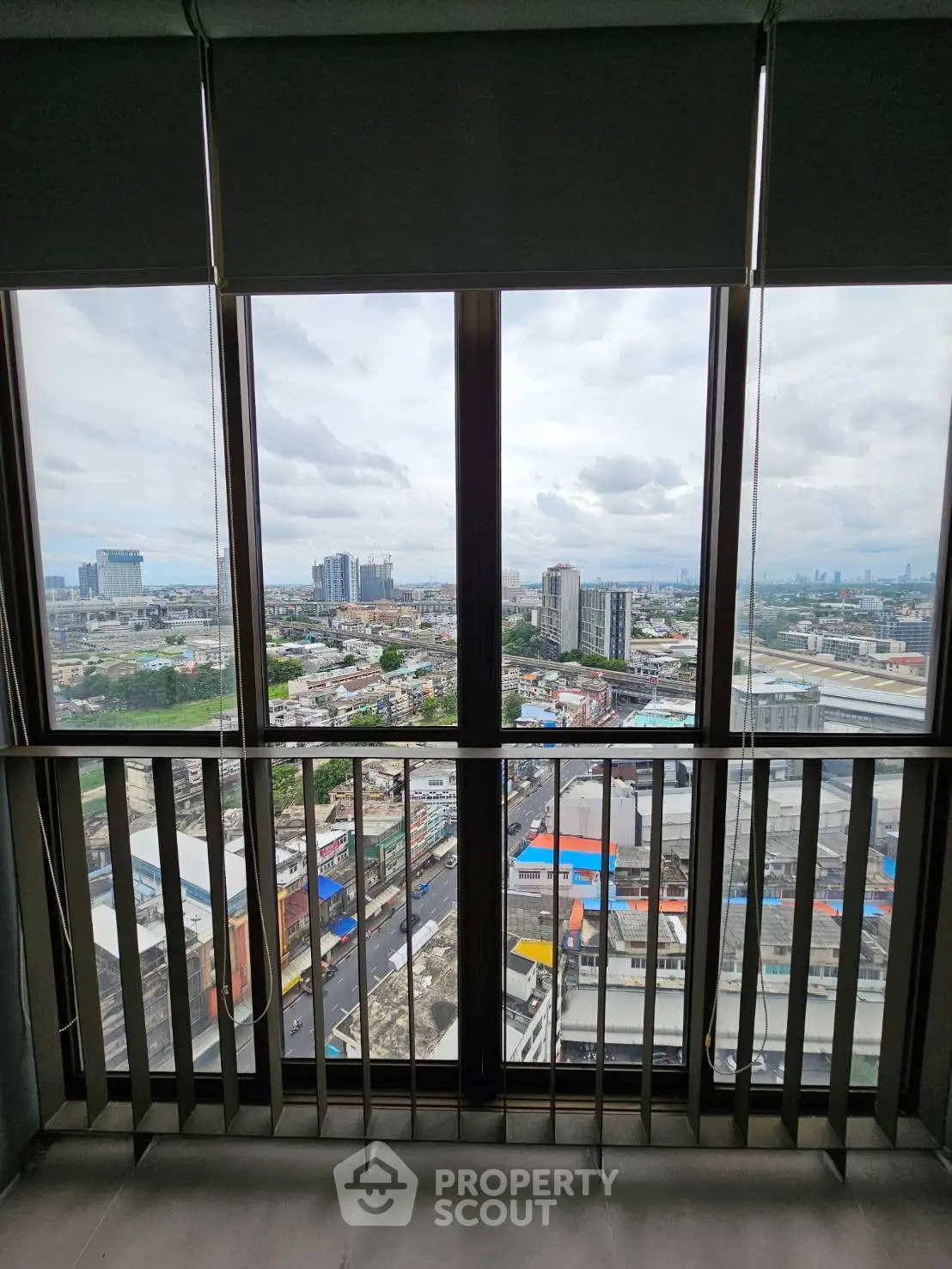 Stunning cityscape view from high-rise apartment balcony with expansive windows.