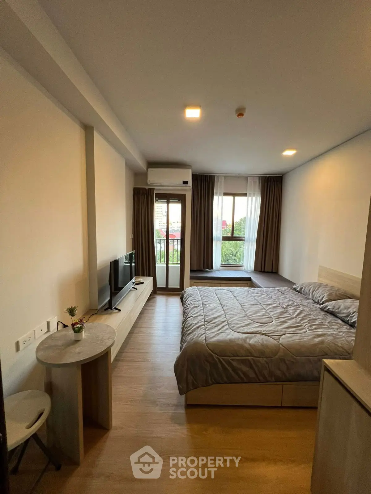 Modern bedroom with balcony access and natural light, featuring a cozy bed and sleek furnishings.
