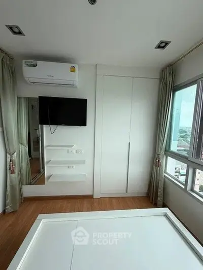 Modern bedroom with air conditioning, TV, and large window offering city views.