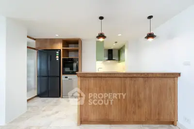 Modern kitchen with wooden cabinetry, sleek black appliances, and stylish pendant lighting.