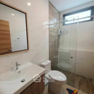 Modern bathroom with glass shower, sleek vanity, and natural light.