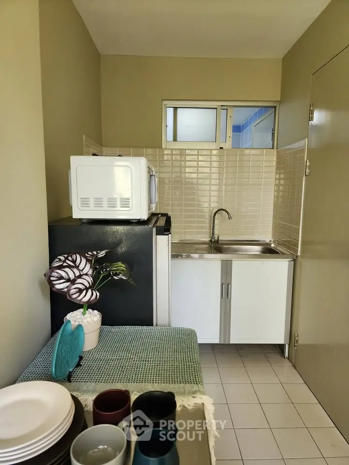 Compact kitchen with modern appliances and tiled backsplash in cozy apartment.